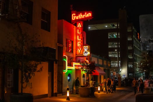 Vibrant night street scene with neon signs at Bakerville's Guthrie's Alley Cat.