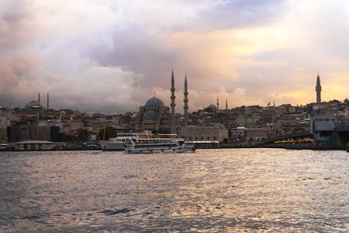 Boats moored in Eminonu Pier at the mouth of the Golden Horn Bay and the Eminonu district skyline with the Suleymaniye mosque in the background.