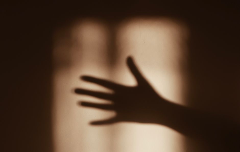 Shadow of a hand cast on a sepia-toned wall, creating a dramatic silhouette.