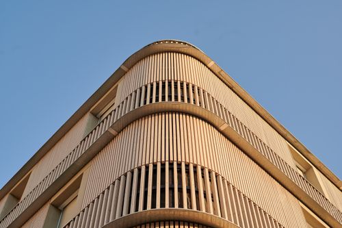 Free Contemporary building facade with wooden elements against a clear blue sky. Stock Photo