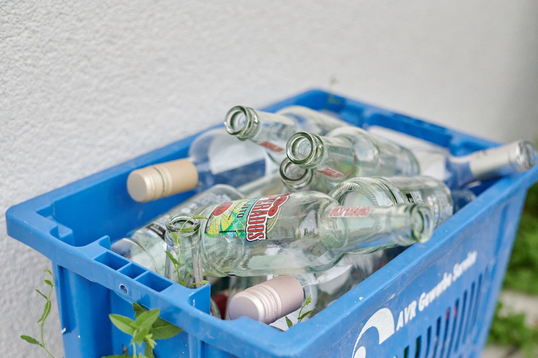 Blue crate filled with empty glass bottles ready for recycling. Eco-friendly waste management concept.