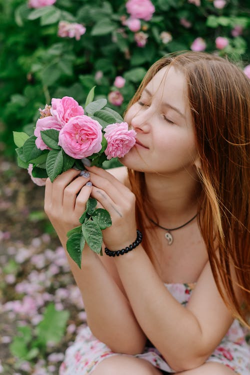 Young Redhead Woman Smelling Roses