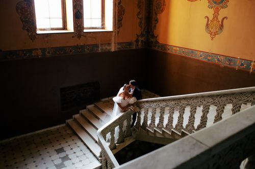 Free Romantic portrait of a newlywed couple embracing on a historic staircase. Stock Photo