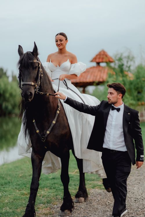 Free Bride on horseback led by groom in a scenic outdoor wedding setting. Stock Photo