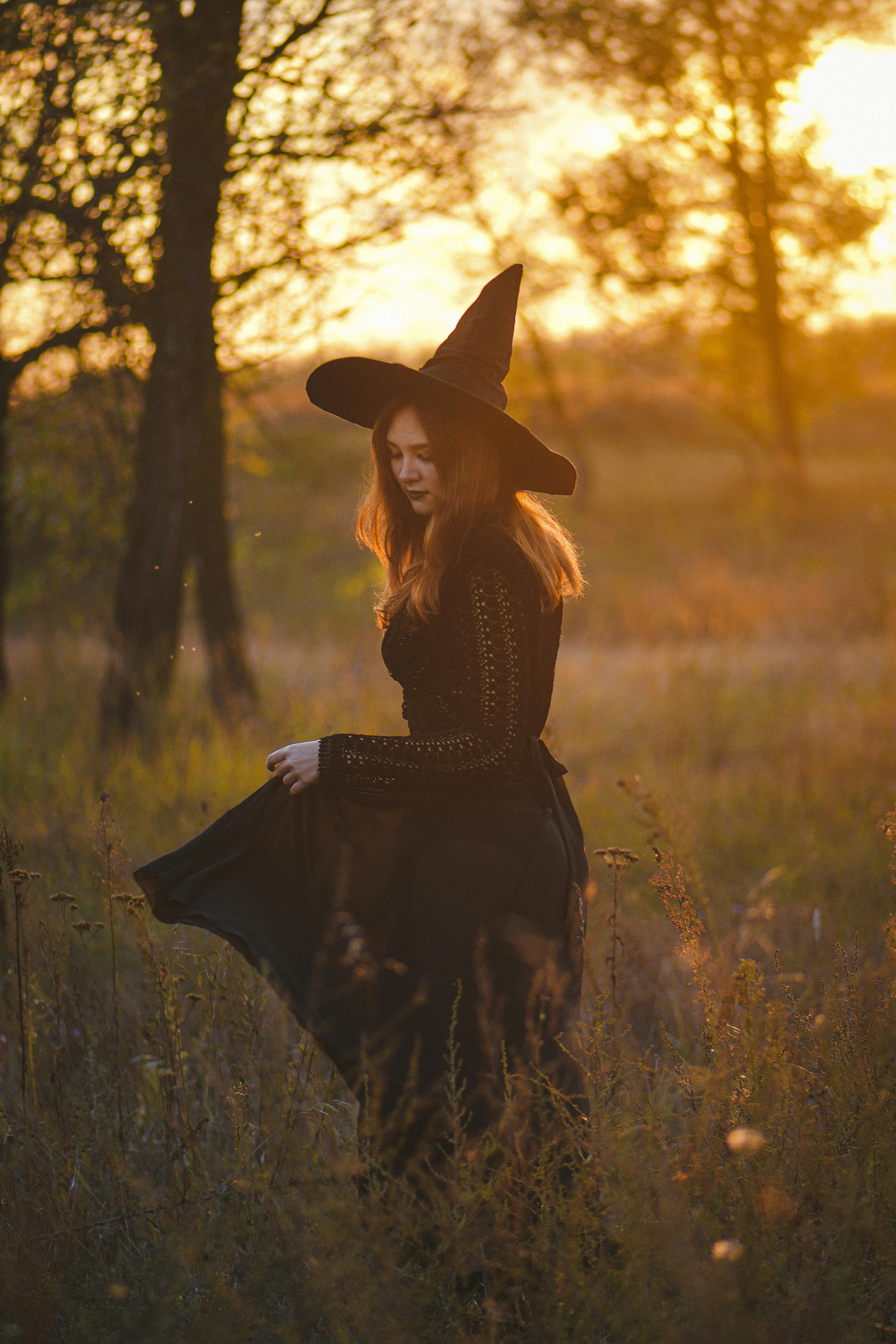 woman in a halloween witch costume walking on a field