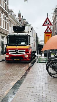 Delivery truck navigating a rainy Amsterdam street, highlighting urban logistics.