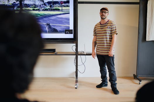 A young man delivers an engaging lecture in a contemporary indoor setting, using technology for visual aids.