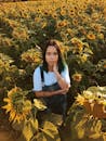 日落时分，一位年轻女子站在生机勃勃的向日葵田里，捕捉着大自然的美丽