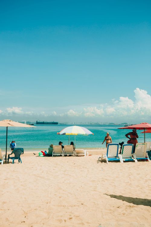Free Beach scene with sunbeds and umbrellas under a clear blue sky, perfect summer relaxation. Stock Photo