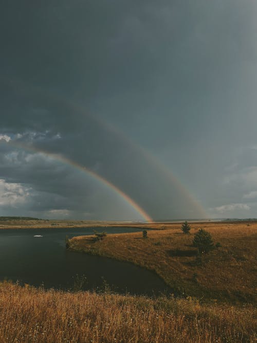 Double Rainbow above River Running through Field