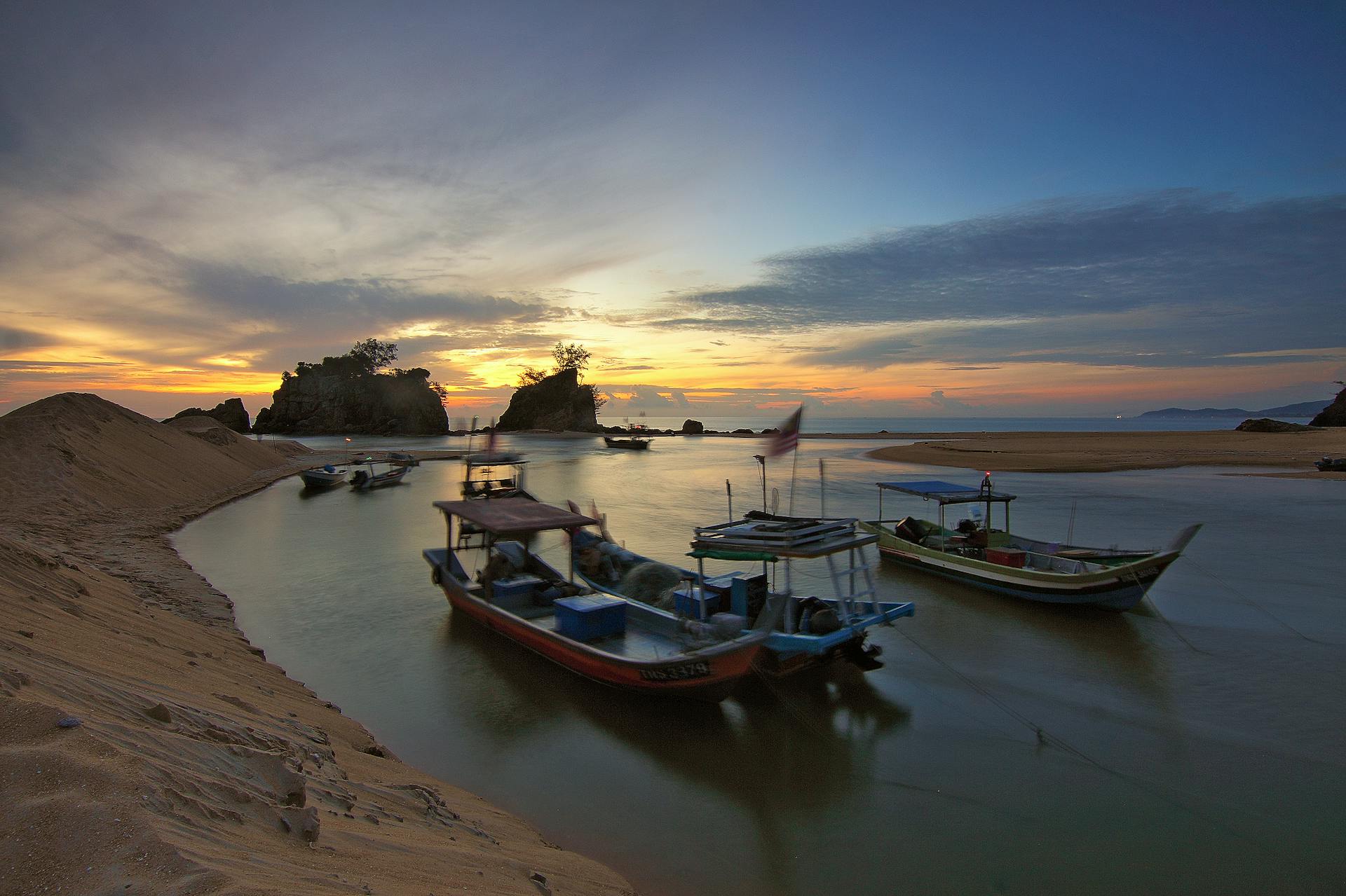 Tranquil scene of fishing boats at sunset by a tropical island shore, showcasing natural beauty.