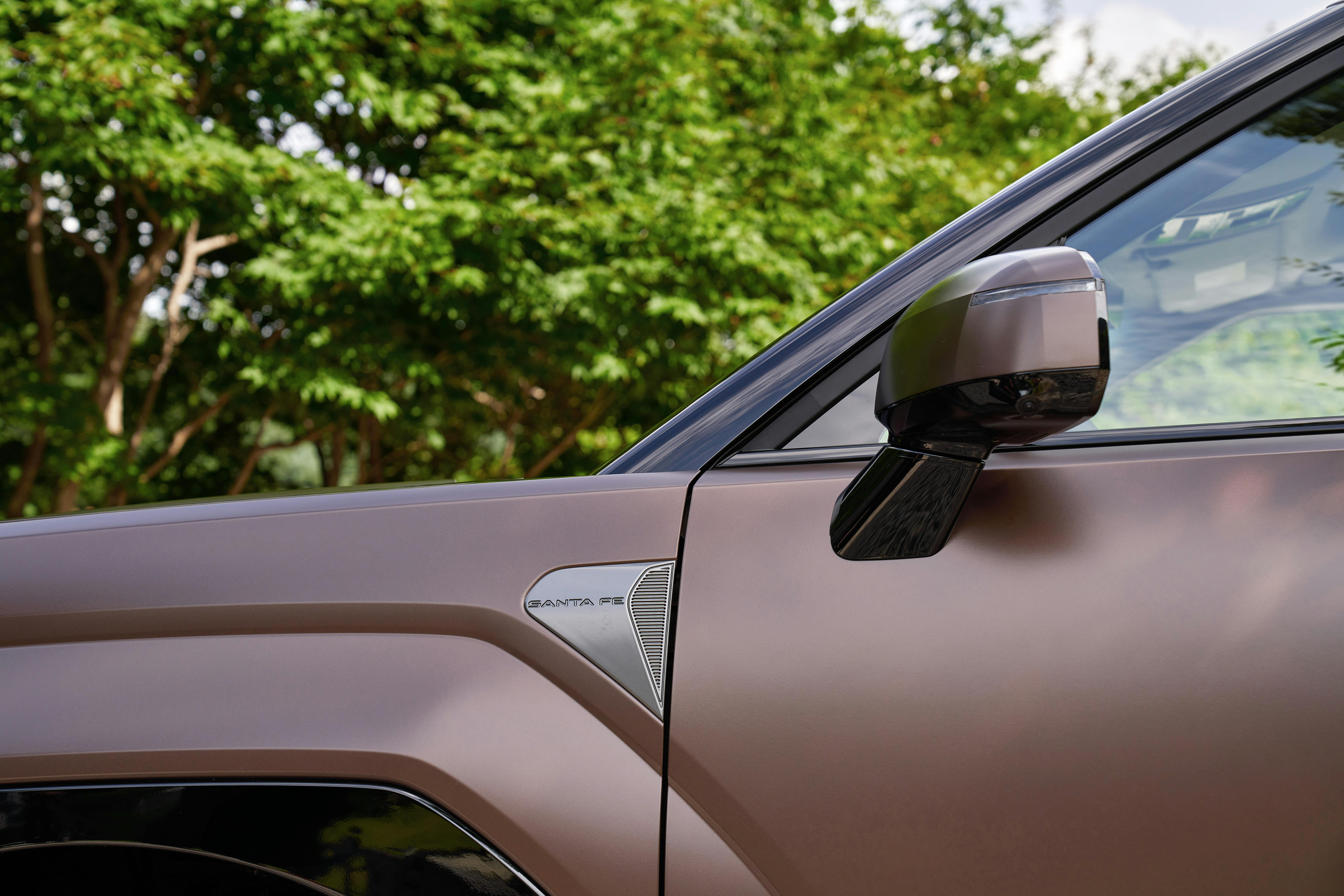 Close-up of a modern SUV with lush green background, showcasing sleek design.