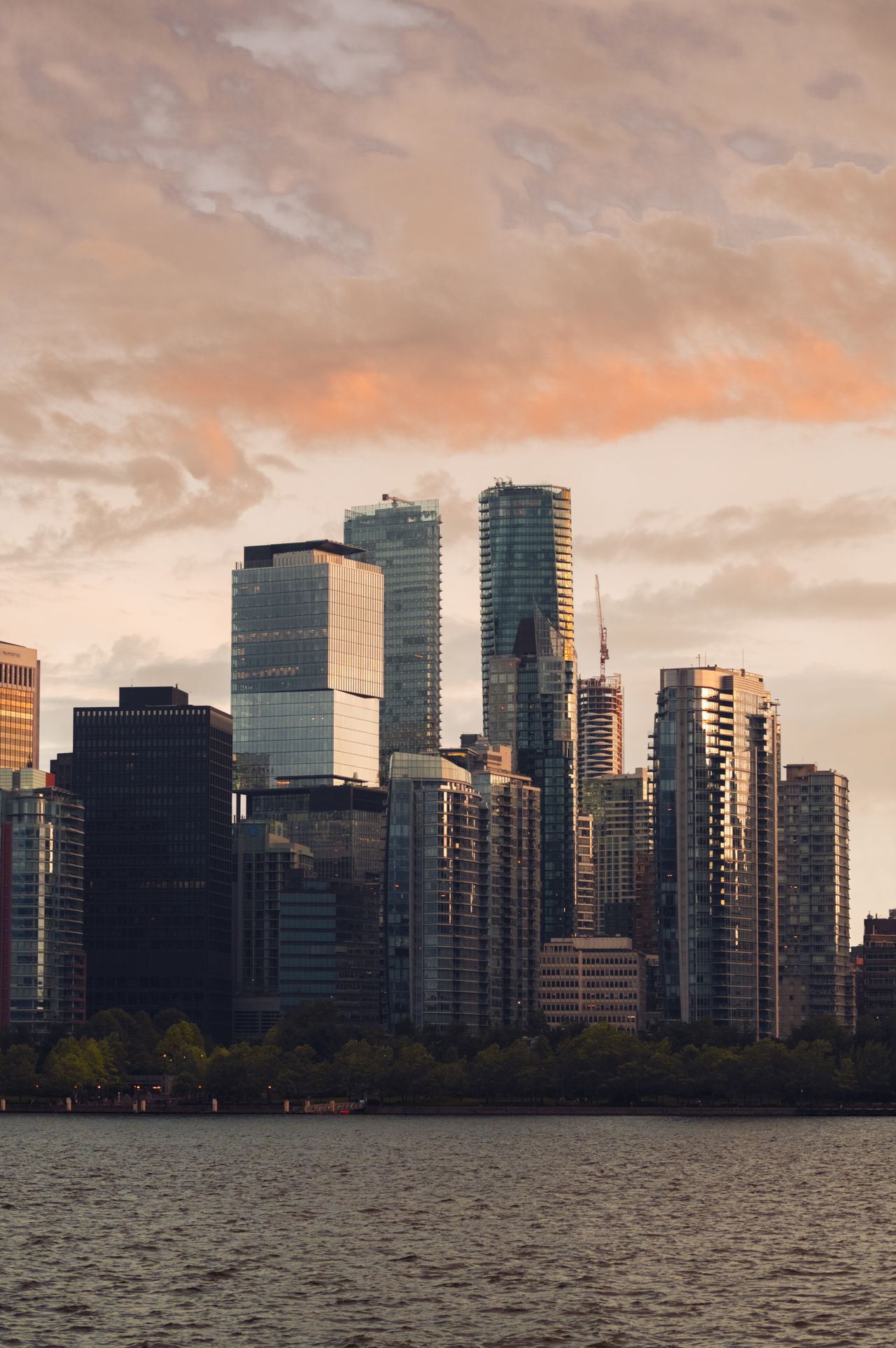 Captivating view of a modern city skyline with skyscrapers at sunset reflecting on the waterfront.