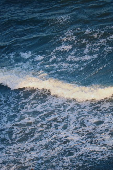 Captivating aerial shot of ocean waves crashing, showcasing dynamic foam and blue waters.