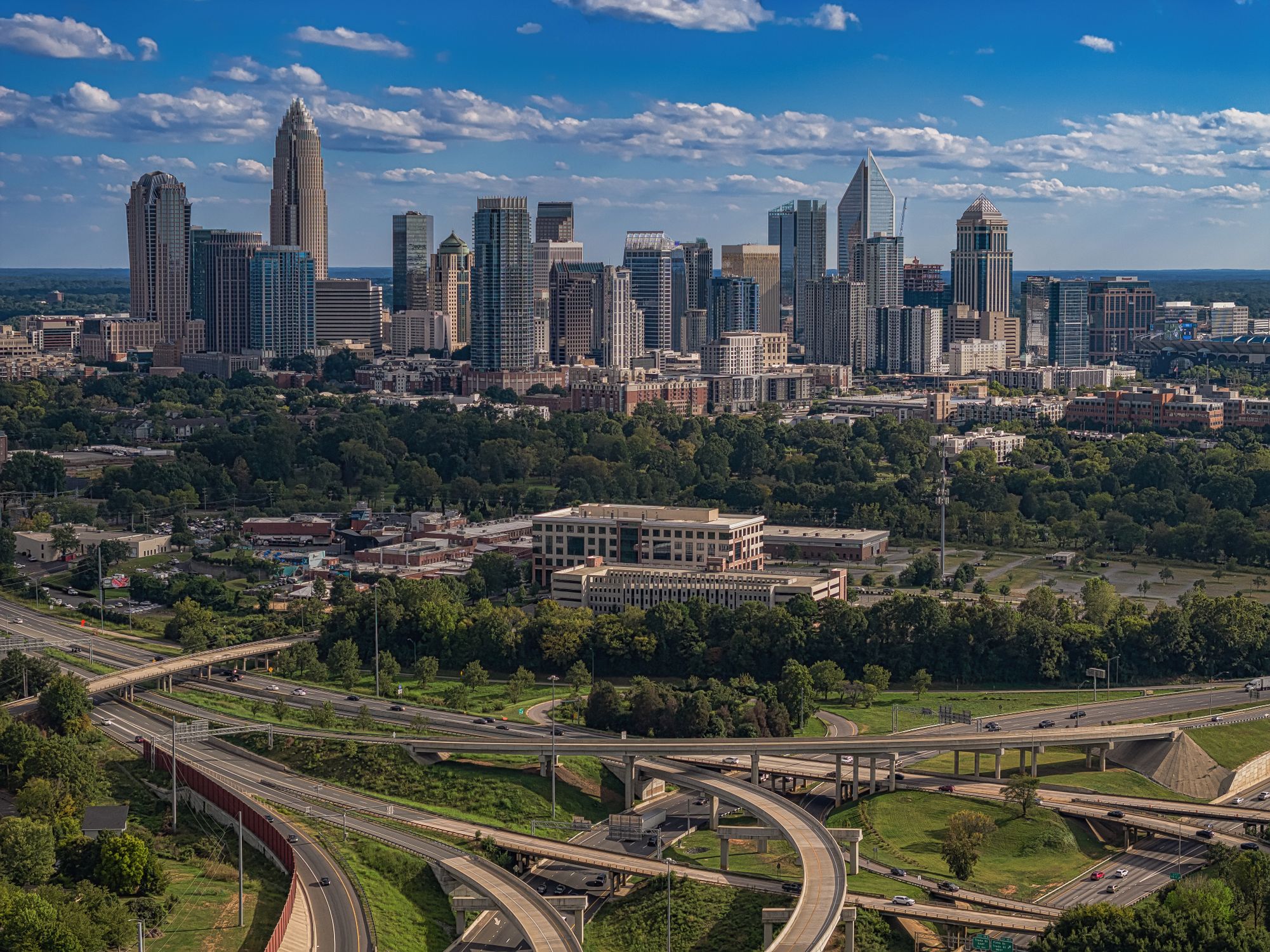 A vibrant view of Charlotte's modern skyline and highways on a sunny summer day.