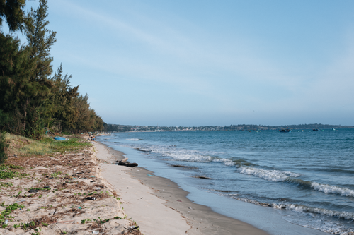 Free Peaceful beach scene with waves lapping the sandy shore under a clear sky. Stock Photo