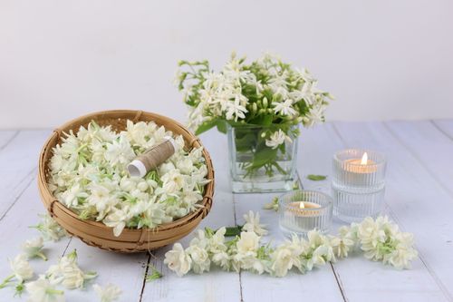 Free Fresh jasmine flowers in a basket with lit candles, creating a serene aromatherapy environment. Stock Photo