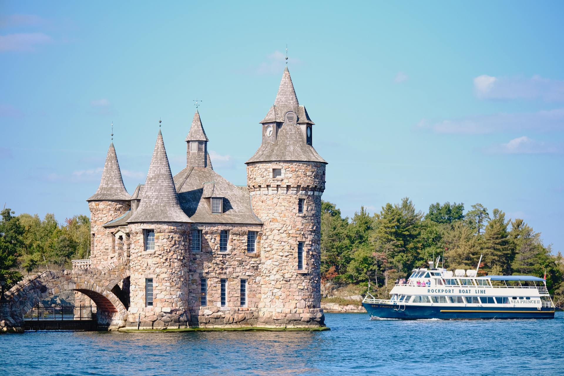 Scenic view of Boldt Castle and tour boat on St. Lawrence River, showcasing historic architecture and serene water setting.