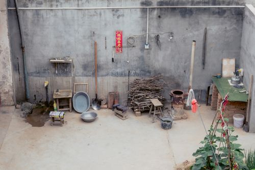 Free A rustic outdoor kitchen setup with tools, bowls, and firewood against a vintage wall. Stock Photo
