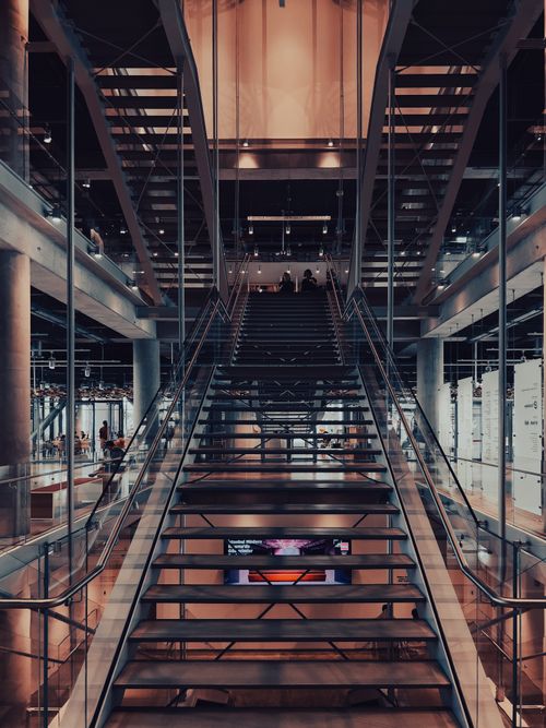 Free Glass and steel staircase in a modern shopping mall interior with unique design elements. Stock Photo
