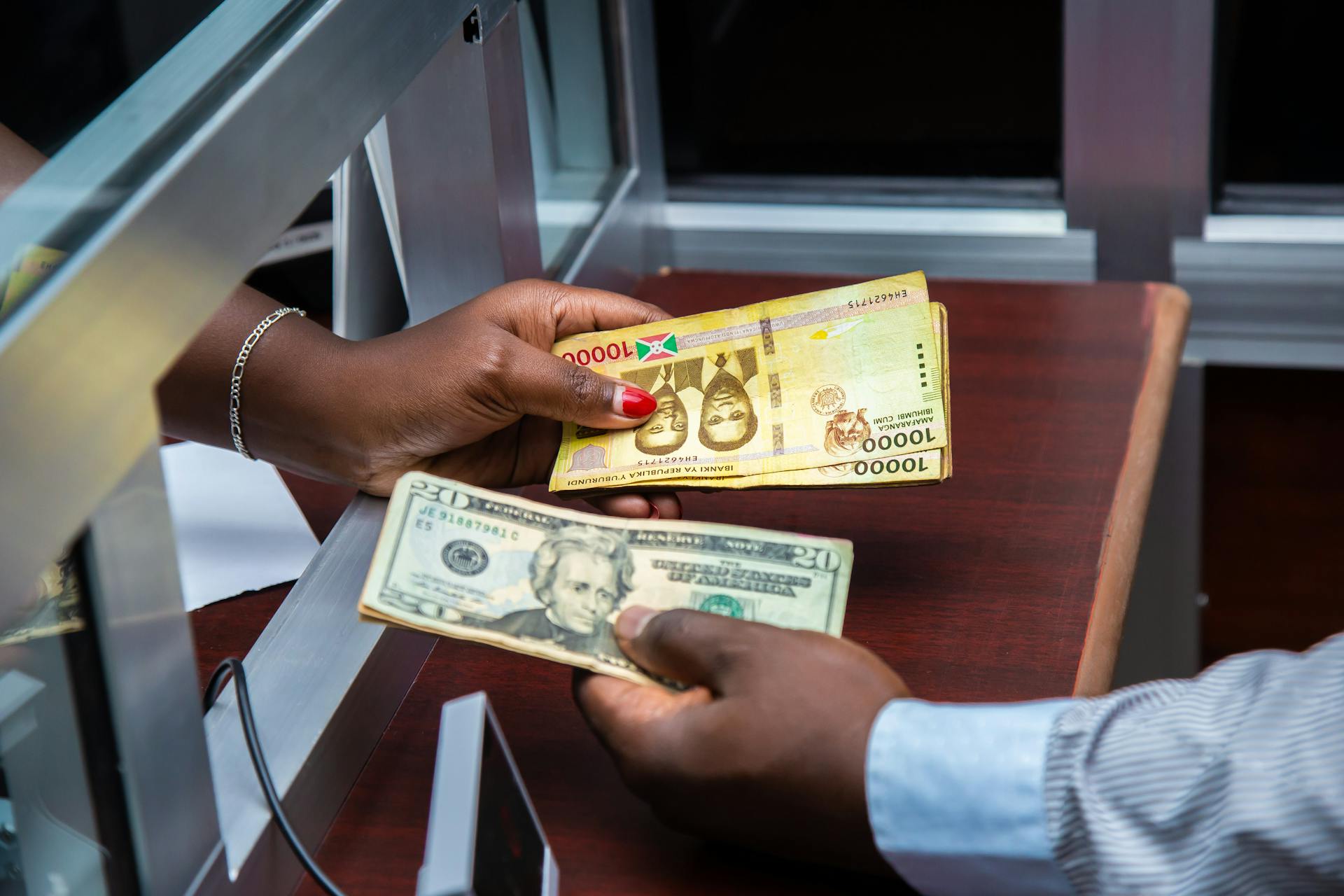 Burundian franc and US dollar exchange transaction at bank counter.