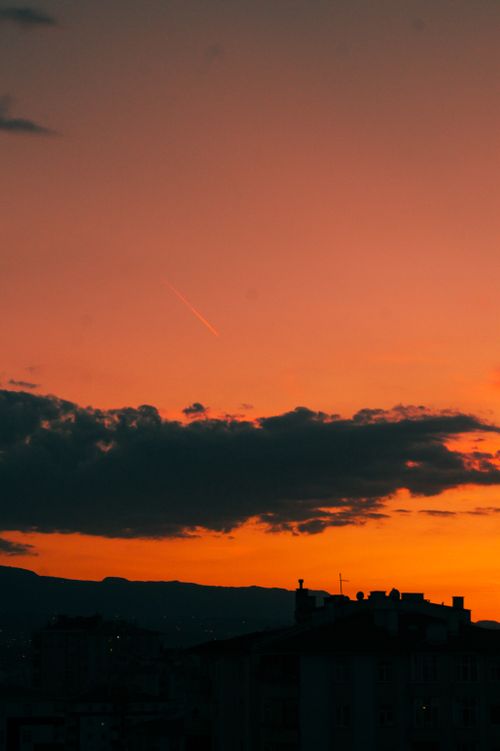 Free A stunning sunset with dramatic clouds and silhouettes of urban buildings. Stock Photo