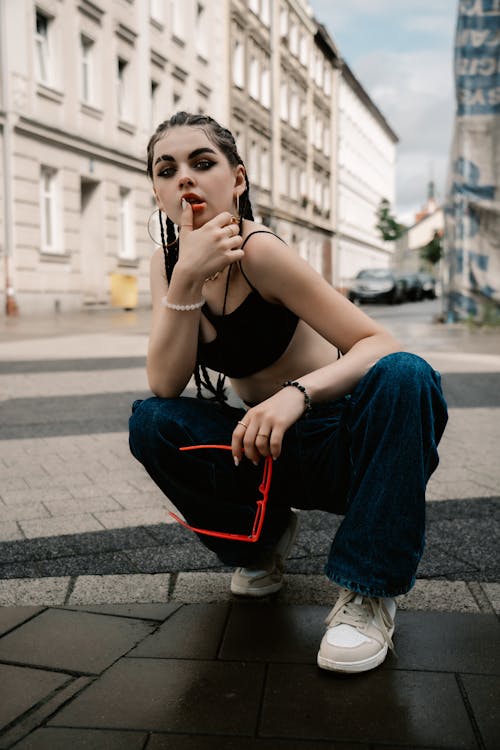 Portrait of a Female Model Wearing a Crop Top Crouching on the Pavement