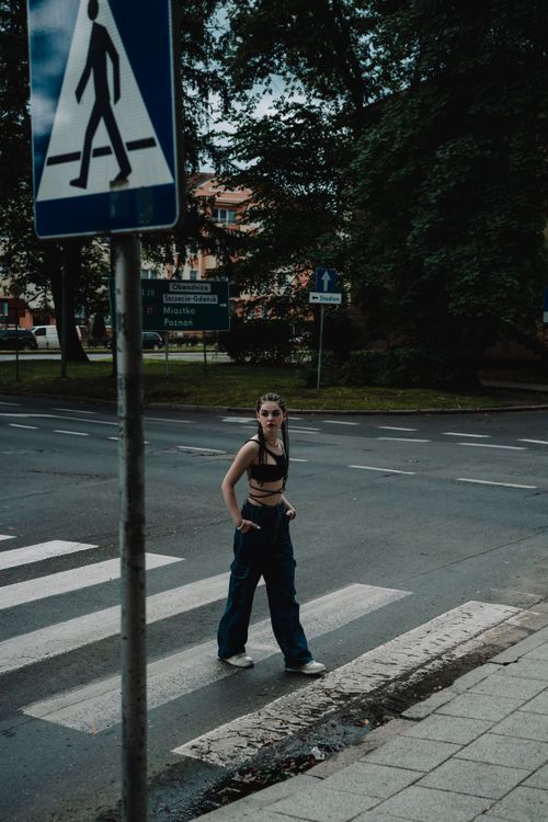Free Young woman with braided hair walks stylishly across a city crosswalk. Stock Photo
