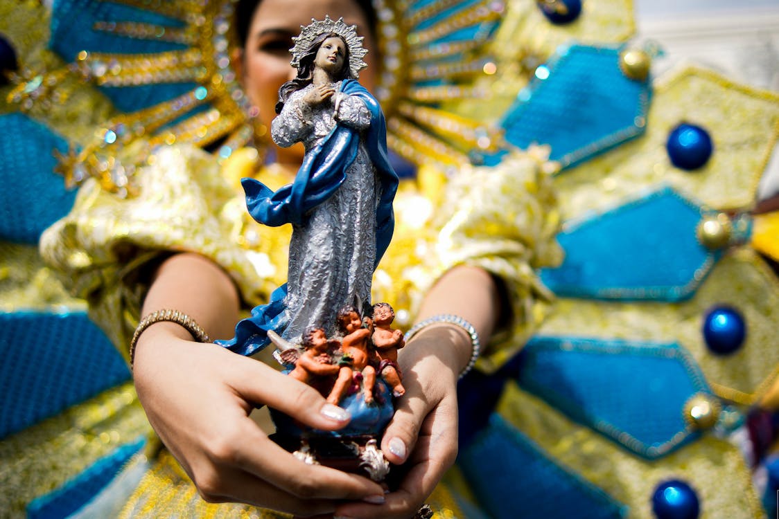 Hands of a Female Dancer Holding a Figurine of Virgin Mary