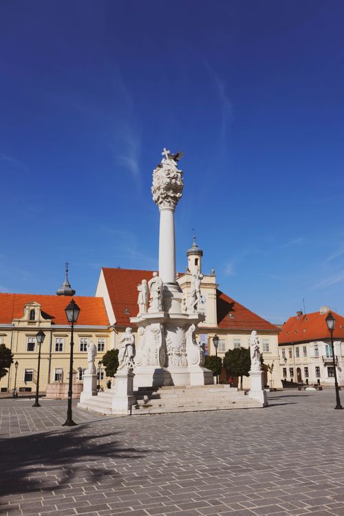 Free View of the Holy Trinity Statue in Osijek, Croatia, with historic architecture surrounding the square. Stock Photo