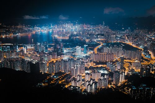 Free A vibrant aerial view of Hong Kong's illuminated skyscrapers and harbor at night. Stock Photo