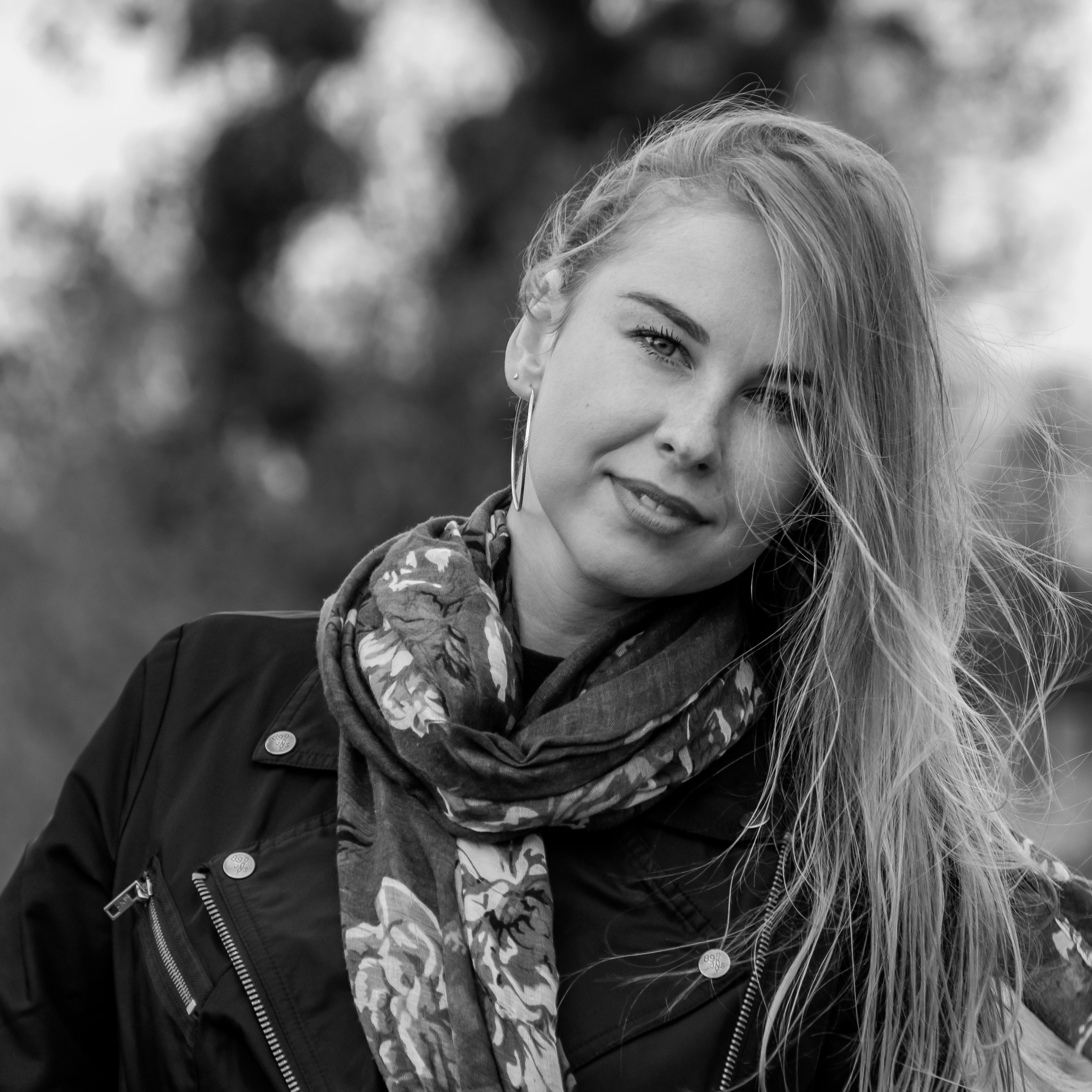 Elegant black and white portrait of a smiling woman with long blonde hair and floral scarf.