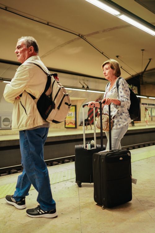 Free Elderly couple with luggage at a Lisbon subway platform, poised for travel adventure. Stock Photo