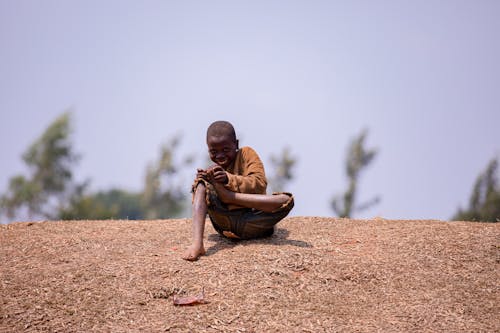 A Boy Sitting on the Ground and Smiling 