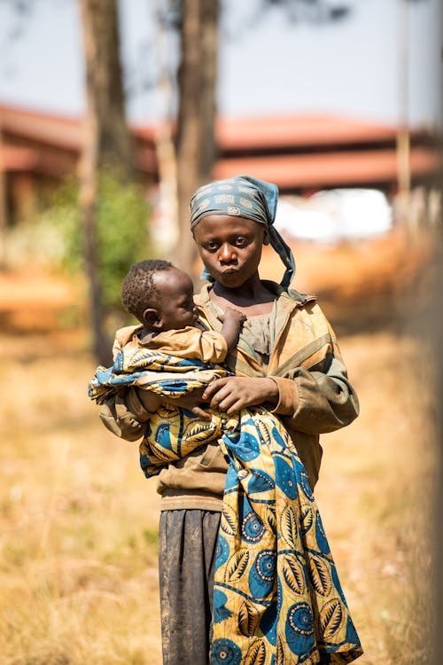 Girl with Headscarf Holding Baby in Hands