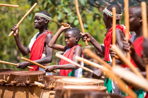 Free Group of African men and boy playing drums in traditional clothing outdoors. Stock Photo