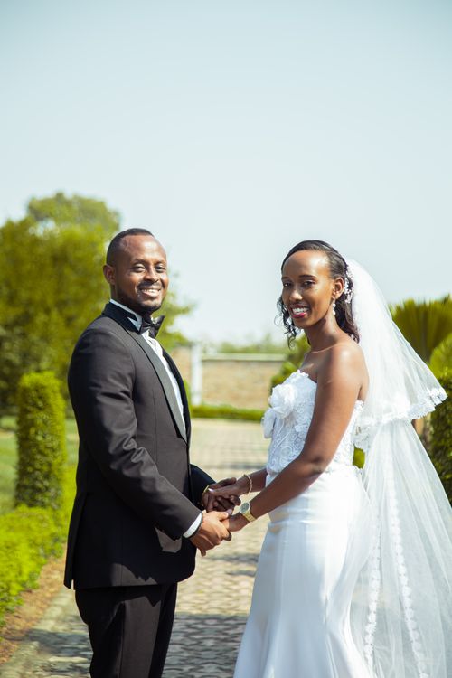 Free Elegant portrait of a smiling newlywed couple holding hands outdoors. Stock Photo