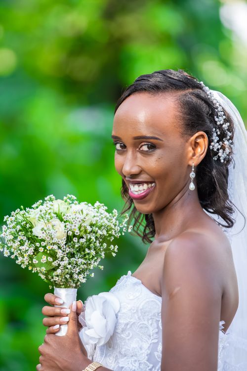 Free Radiant bride smiling holding floral bouquet in an outdoor setting. Stock Photo