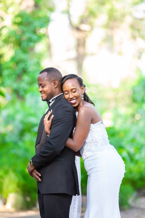 Free Smiling bride embraces groom in a lush garden setting, showcasing love and happiness. Stock Photo