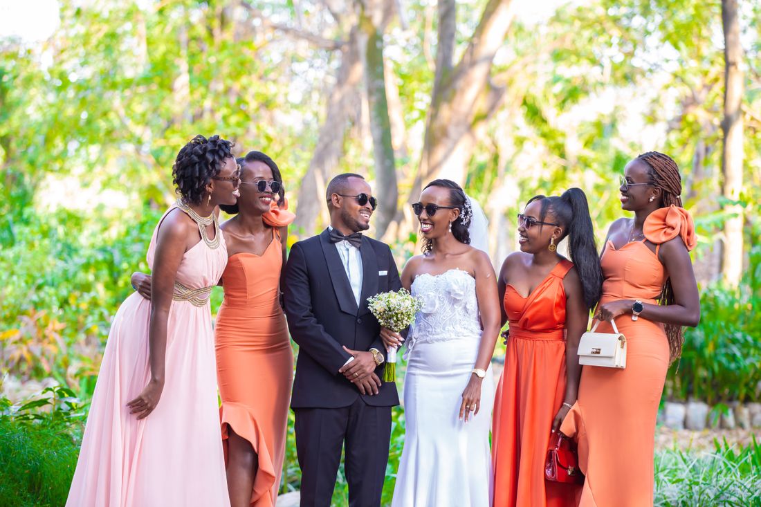 Cheerful newlyweds standing among their bridesmaids