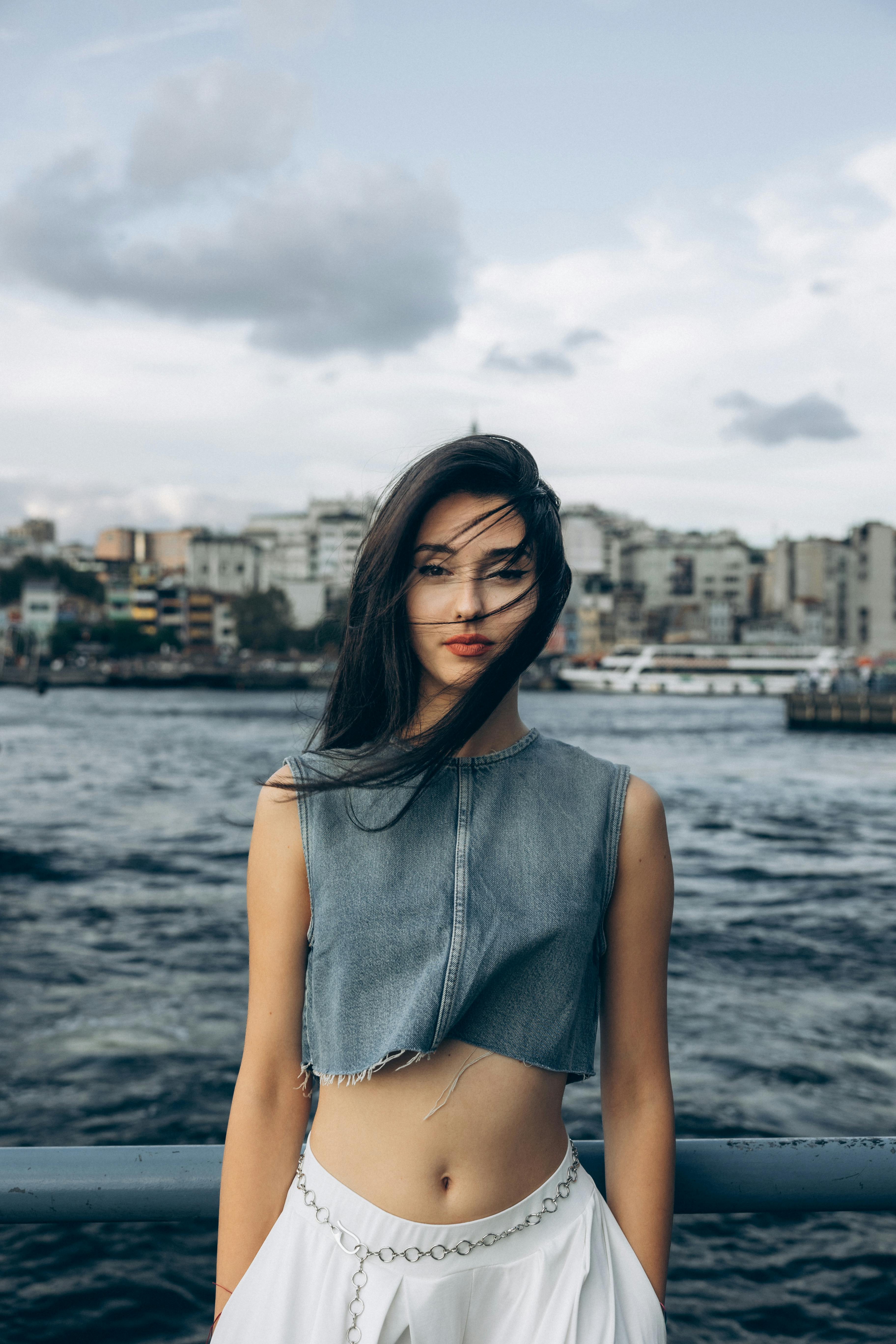 a woman in a crop top and skirt standing on a pier