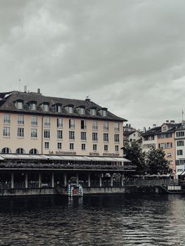Historic buildings along Zurich's canal with cloudy sky, perfect blend of architecture and water.