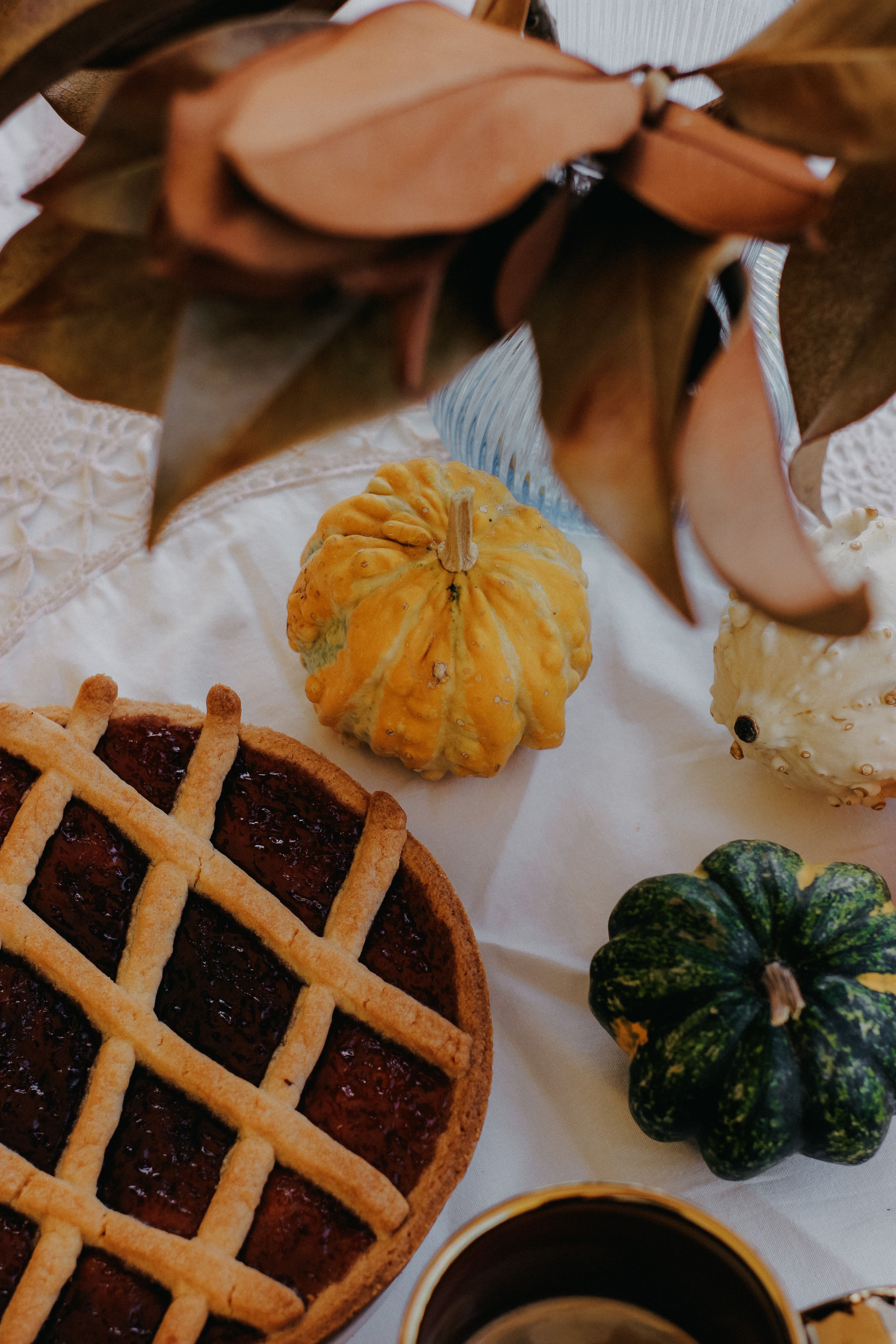 Warm and cozy autumn scene featuring a lattice pie, pumpkins, and leaves.