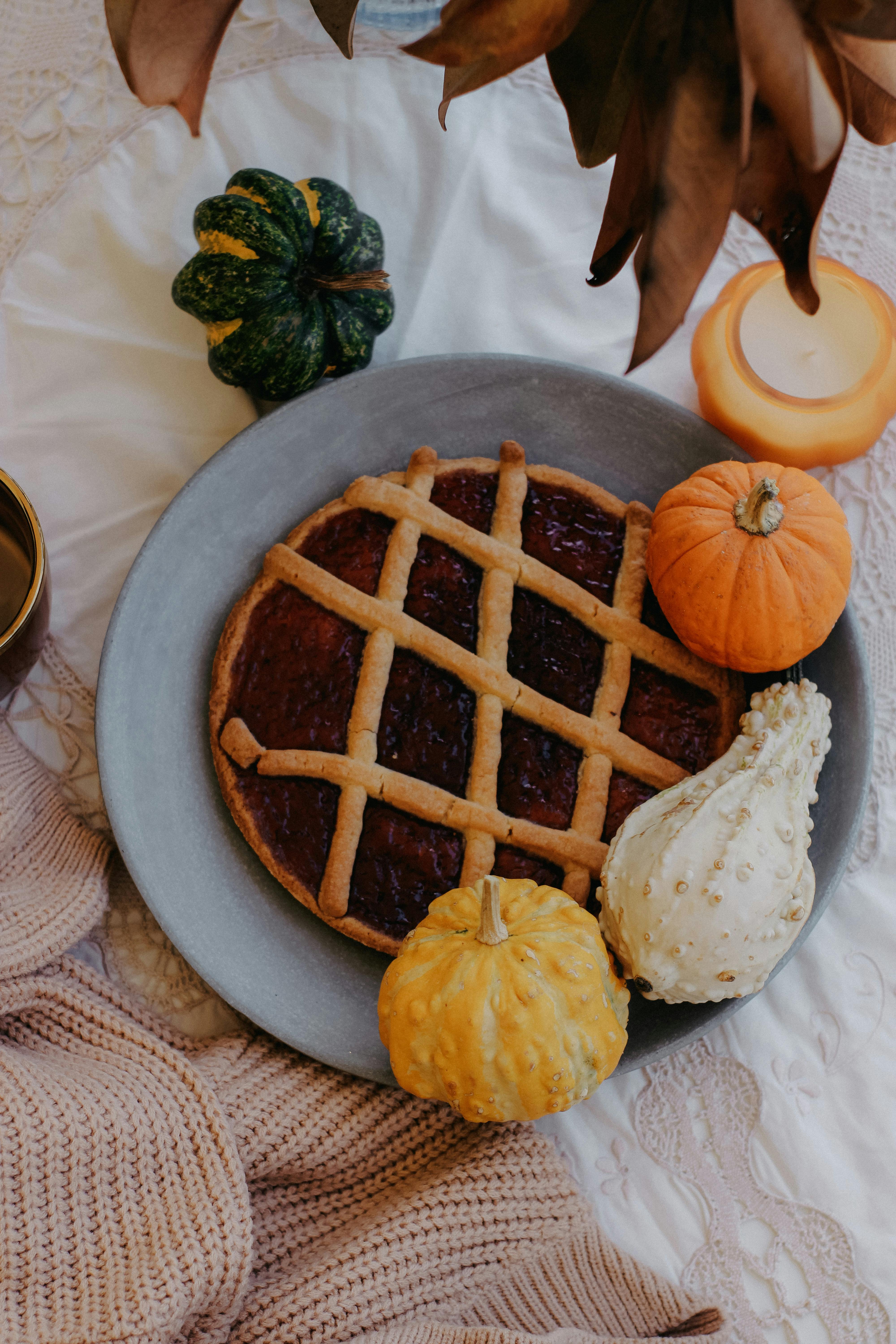 Warm autumn-themed table setting with pumpkin pie, gourds, and cozy decor.