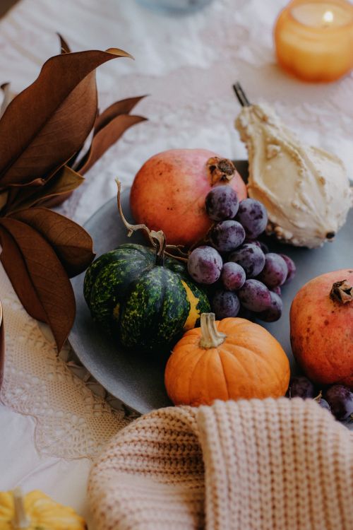 Free A cozy autumn arrangement featuring pumpkins, grapes, and pomegranates on a table with warm decor. Stock Photo