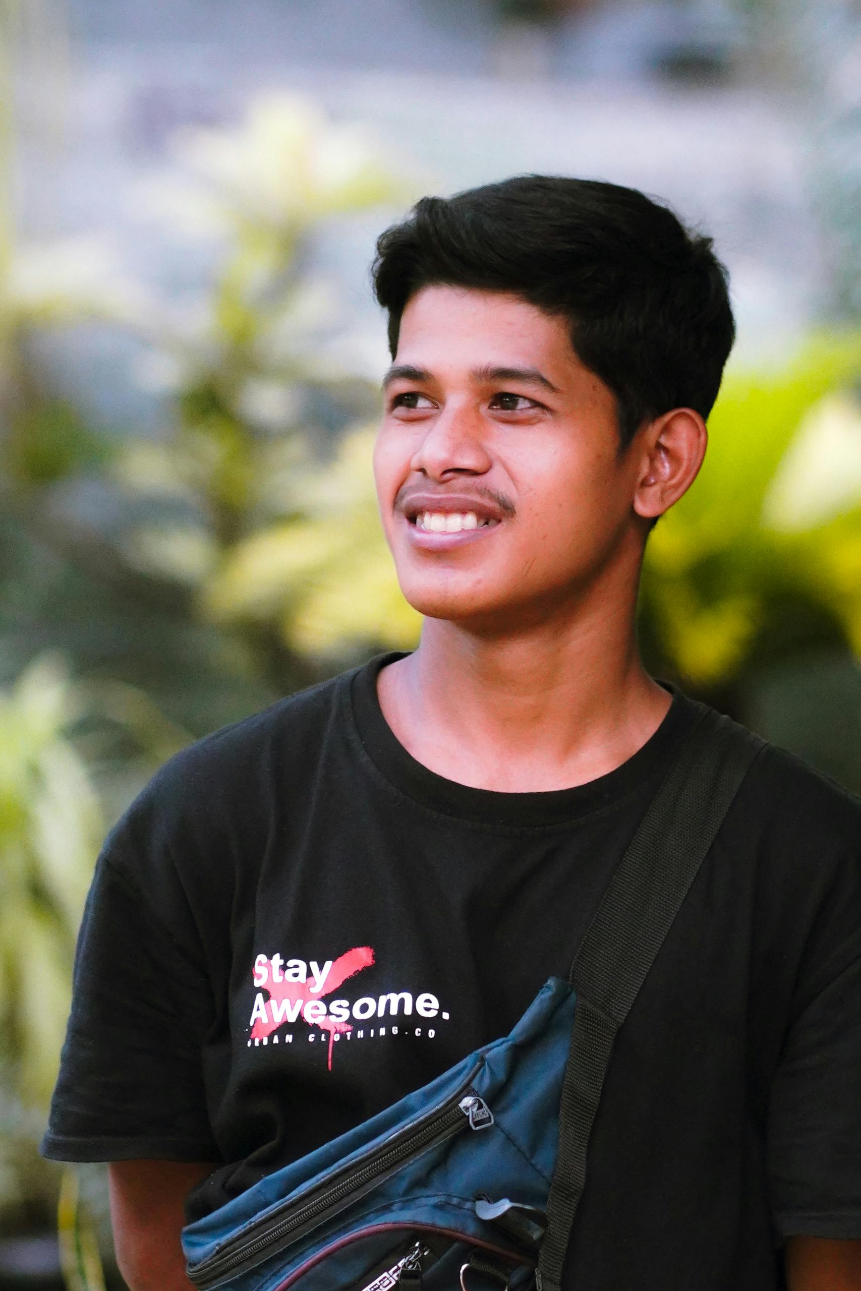 Portrait of a young man smiling outdoors wearing a casual t-shirt, embodying a positive and carefree lifestyle.
