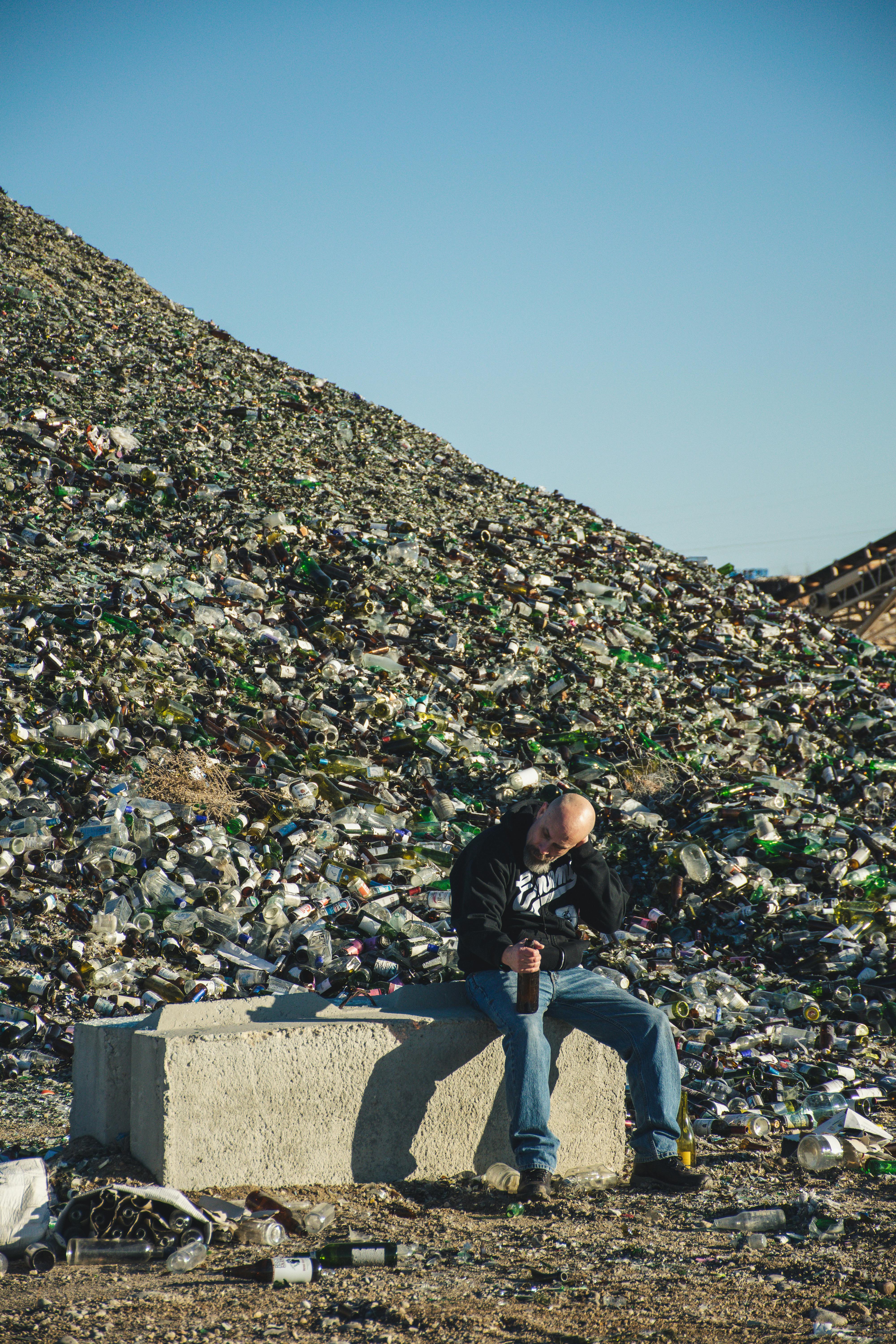 man in black jacket sitting on green concrete