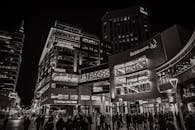 黑白城市街景在夜间呈现，以现代建筑和人群为特色