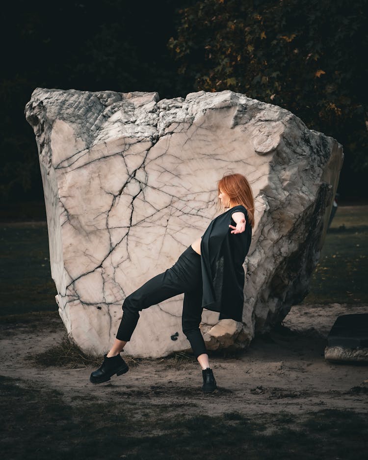 Woman In Black Cardigan And Pants Dancing By A Marble Slab