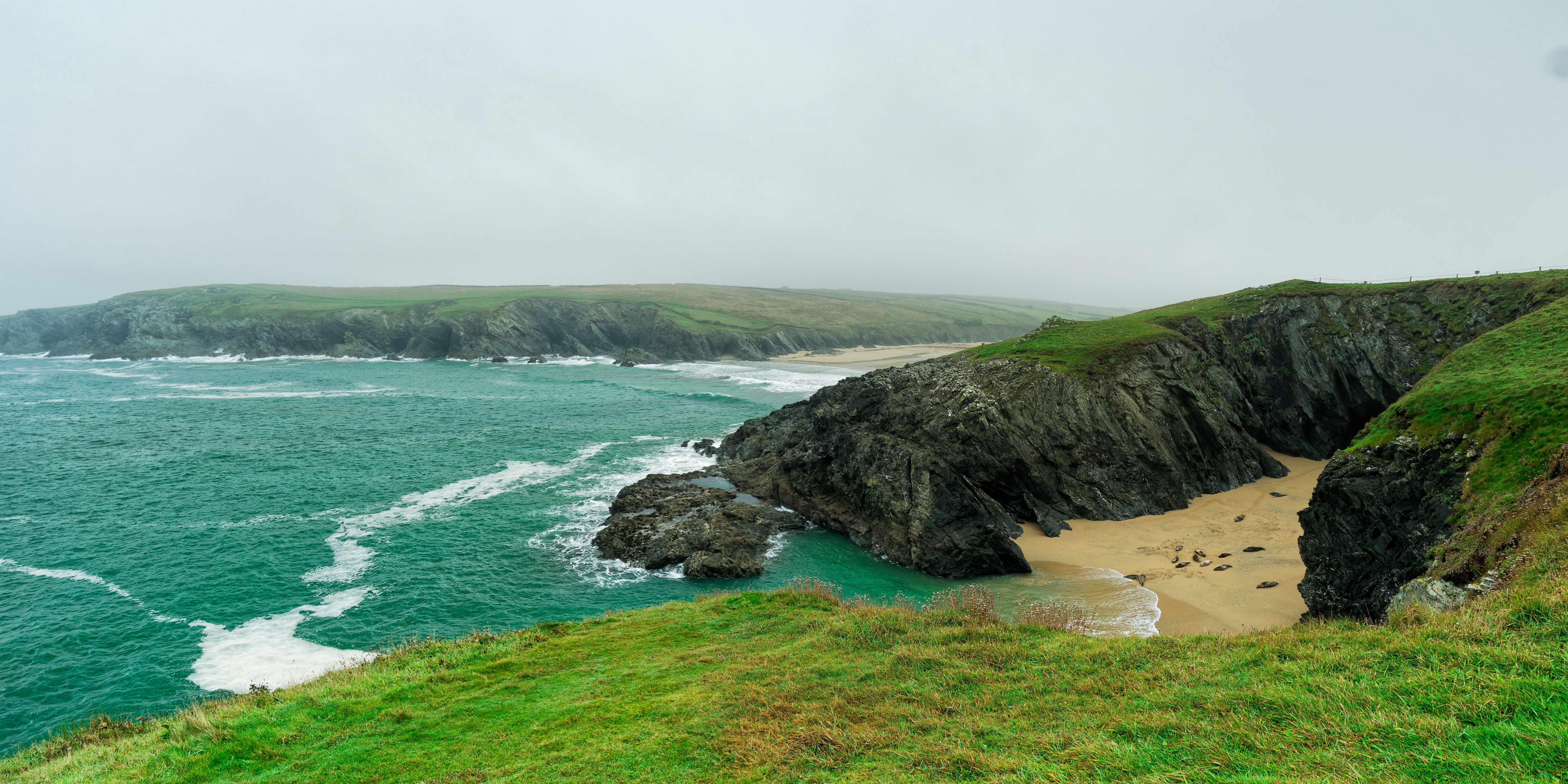 Breathtaking view of Trevaunance Cove's rugged cliffs and turquoise sea in Cornwall, England.
